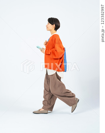 スマホを持って歩くおしゃれなミドル女性の全身写真 123382997