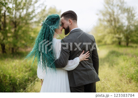 a bearded groom and a girl with green hair are walking 123383784