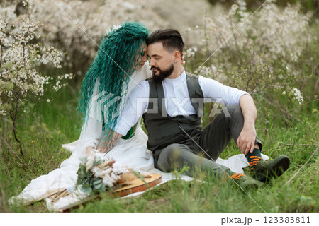 a bearded groom plays a stringed instrument and a girl sits in a spring meadow 123383811
