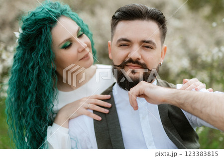 a bearded groom plays a stringed instrument and a girl sits in a spring meadow a bearded groom plays a stringed instrument and a girl sits in a spring meadow 123383815