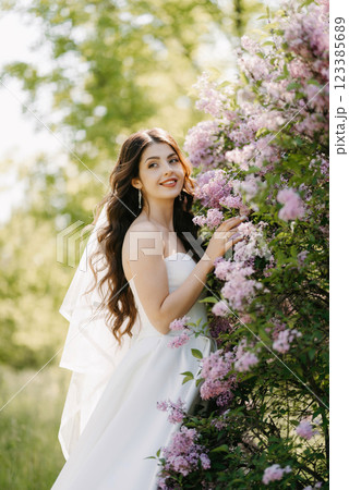 young girl bride in a white dress in a spring forest in lilac bushes young girl bride in a white dress in a spring forest in lilac bushes 123385689