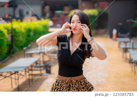 A cute smiling woman wearing a black dress and a tiger-print skirt in an outdoor cafe. 123385783