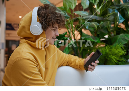 Teenage boy watching funny video on smartphone in shopping mall Teenage boy watching funny video on smartphone in shopping mall 123385978