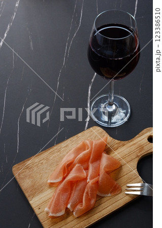 赤ワインのグラスと、カッティングボードに盛った生ハム 123386510