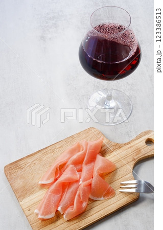 赤ワインのグラスと、カッティングボードに盛った生ハム 赤ワインのグラスと、カッティングボードに盛った生ハム 123386513