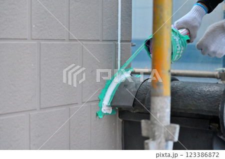 養生テープの巻き取りをする職人　コーキング打ち替え　外壁塗装　マスキングテープ　 123386872