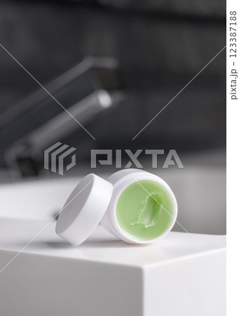 Lip balm jar with blank lid on basin in dark grey modern bathroom close up, cosmetic mockup Lip balm jar with blank lid on basin in dark grey modern bathroom close up, cosmetic mockup 123387188
