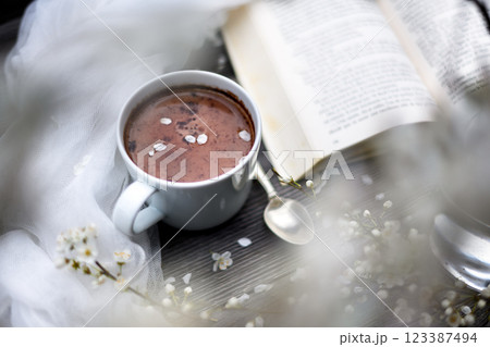 Cup of aromatic hot chocolate with book and cherry flowers 123387494