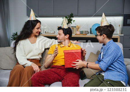 Friends celebrate a birthday with party hats, gifts, and cheerful smiles 123388231