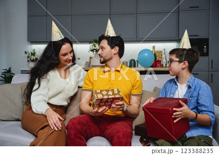 Family celebration at home with birthday hats and gifts in cozy living room Family celebration at home with birthday hats and gifts in cozy living room 123388235