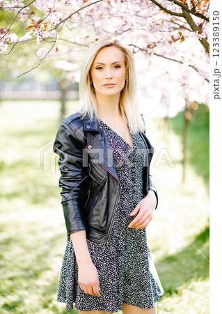 Beautiful blonde model posing under blooming tree in spring 123389150