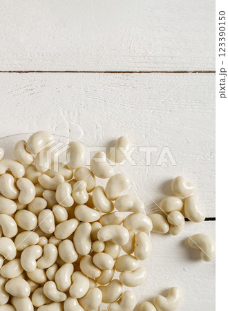 Cashew nuts in milk chocolate on a white wooden background. 123390150