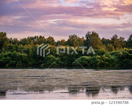 Sunset over tranquil river reflecting soft colors, surrounded by lush greenery and serene atmosphere Sunset over tranquil river reflecting soft colors, surrounded by lush greenery and serene atmosphere 123390786