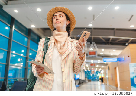 Bottom view of young Caucasian elegant woman using smartphone and holds boarding pass for the plane in airport. Concept of flight and travel Bottom view of young Caucasian elegant woman using smartphone and holds boarding pass for the plane in airport. Concept of flight and travel 123390827