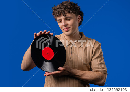 Handsome Man Dancing Vinyl Record Disc On blue. Hobby, Music Lover, Collection Handsome Man Dancing Vinyl Record Disc On blue. Hobby, Music Lover, Collection 123392198