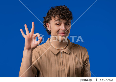 Positive mature 30s man makes OK, okay hand sign gesture.Happy student on blue 123392208