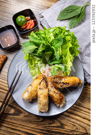 A bird's-eye view of traditional Vietnamese crispy spring rolls served with mint leaves, lettuce, and fish sauce A bird's-eye view of traditional Vietnamese crispy spring rolls served with mint leaves, lettuce, and fish sauce 123392932