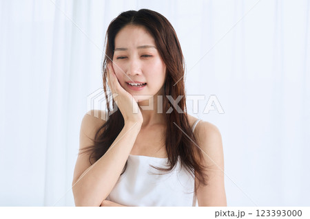 歯が痛くて頬を抑える女性 123393000