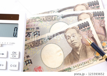 福沢諭吉の肖像の一万円紙幣と電卓 123393652