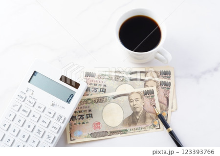 福沢諭吉の肖像の一万円紙幣と電卓、淹れたてのコーヒー 福沢諭吉の肖像の一万円紙幣と電卓、淹れたてのコーヒー 123393766