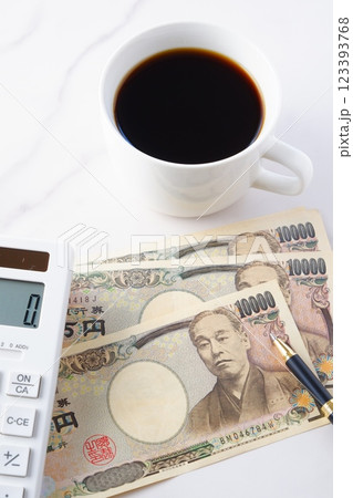 福沢諭吉の肖像の一万円紙幣と電卓、淹れたてのコーヒー 123393768