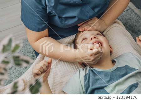 boy lying on soft white blanket during speech therapy session with female therapist in cozy room, concept of speech correction, childhood development, and healthcare 123394176