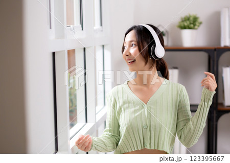 Portrait happy young woman wearing headphones listening music while standing with fun and enjoy. 123395667