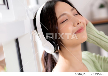 Portrait happy young woman wearing headphones listening music while standing with fun and enjoy. Portrait happy young woman wearing headphones listening music while standing with fun and enjoy. 123395668