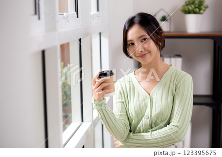 Portrait young asian woman relax and enjoyment with drinking coffee by the window in living room. Portrait young asian woman relax and enjoyment with drinking coffee by the window in living room. 123395675