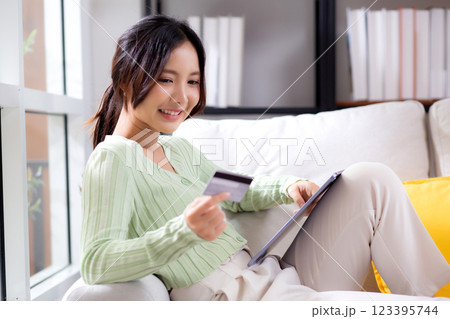 Young asian woman sitting on sofa using tablet computer shopping online with credit card. 123395744
