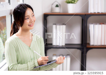 Young asian woman using tablet writing with inspiration and comfortable by window. 123395915