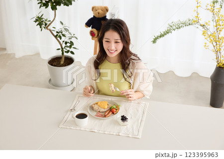 ダイニングで朝ごはんを食べる女性 123395963