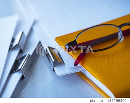テーブルに置かれた書類と手帳とメガネ 123396303