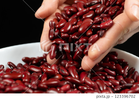 Hands pouring raw uncooked red kidney beans close-up Hands pouring raw uncooked red kidney beans close-up 123396702