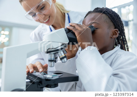 African american teenager looking into microscope during the chemistry lesson African american teenager looking into microscope during the chemistry lesson 123397314