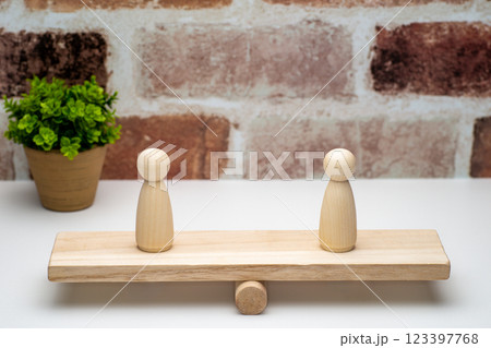 シーソーの上に乗った一体ずつのペグ人形 123397768