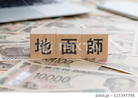 お金の上に地面師と書かれたブロック 123397798
