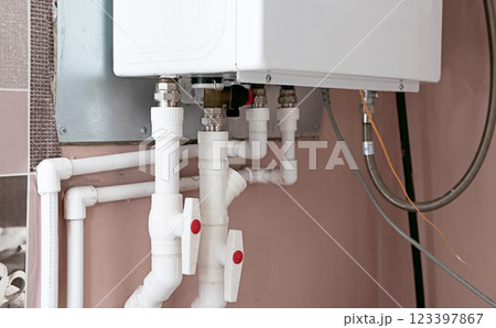 Plumbing system showcasing a modern water heater and connected piping in a residential utility area Plumbing system showcasing a modern water heater and connected piping in a residential utility area 123397867