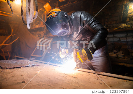 Sculptor uses arc welding to assemble a metal sculpture with proper protection, gloves on and a hard hat. Sparks fly everywhere, hobby Sculptor uses arc welding to assemble a metal sculpture with proper protection, gloves on and a hard hat. Sparks fly everywhere, hobby 123397894