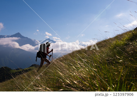 Hiking, travel adventures, tourist recreation in the fresh air, healthy lifestyle, ecotourism. Young woman with a backpack climbs a mountain 123397906