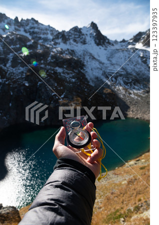 Mountain range and tourist hand with compass on foreground. Nature reserve, travel concept. Landscape photography 123397935