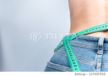 Losing weight is possible. A woman measures her waist after eating or exercising to understand her size. Measurements for sewing clothes 123397938