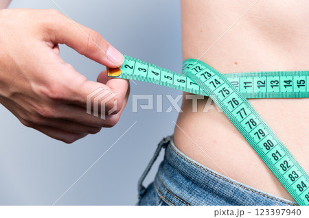 Losing weight is possible. A woman measures her waist after eating or exercising to understand her size. Measurements for sewing clothes 123397940