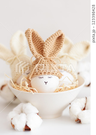 Easter eggs in crochet knitted hats with rabbit ears in nest. Easter celebration concept Easter eggs in crochet knitted hats with rabbit ears in nest. Easter celebration concept 123398428