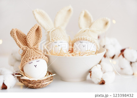 Easter eggs in crochet knitted hats with rabbit ears in nest. Easter celebration concept 123398432
