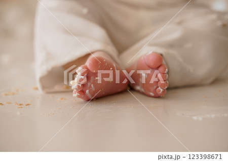 Cute Baby Feet Covered in Messy Cake Icing on a White Surface 123398671