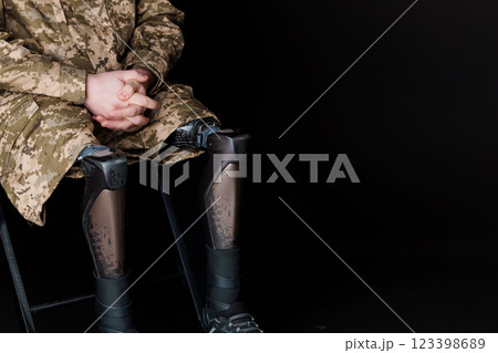 A Service Member with Advanced Bionic Leg Prostheses Sitting in Camouflage Uniform 123398689