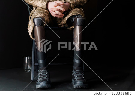 A Soldier in Military Camouflage with Advanced Bionic Leg Prosthesis Resting in a Chair 123398690