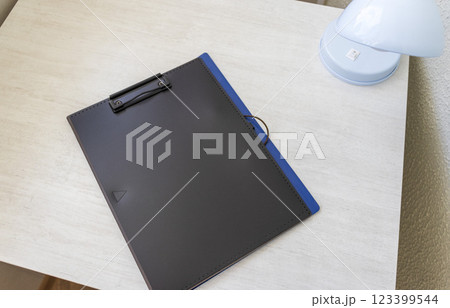Shot of the plastic folder on the office desk with paper clip holder on the top and other office items. A4 size paper mock up. 123399544