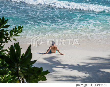 Handsome man sitting on stunning white sand beach 123399660